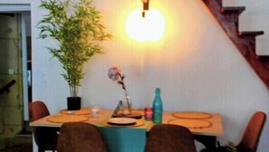 A dining area with a table, chairs, a potted plant, and a staircase.