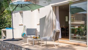 An outdoor patio with a stone wall, a table with a chair, and a large umbrella. - Pretty house with pool in Cagnes-sur-Mer (Cagnes-sur-Mer)