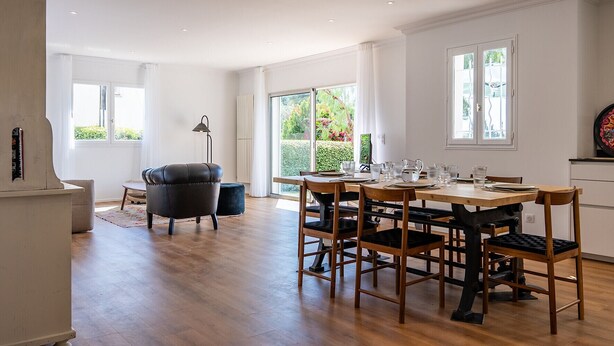 A spacious dining area with a wooden table and chairs, a black leather chair, and a bookshelf. - Pretty house with pool in Cagnes-sur-Mer (Cagnes-sur-Mer)