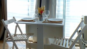Une table à manger dressée avec des assiettes, des couverts et des verres, et un vase de fleurs placé au centre.