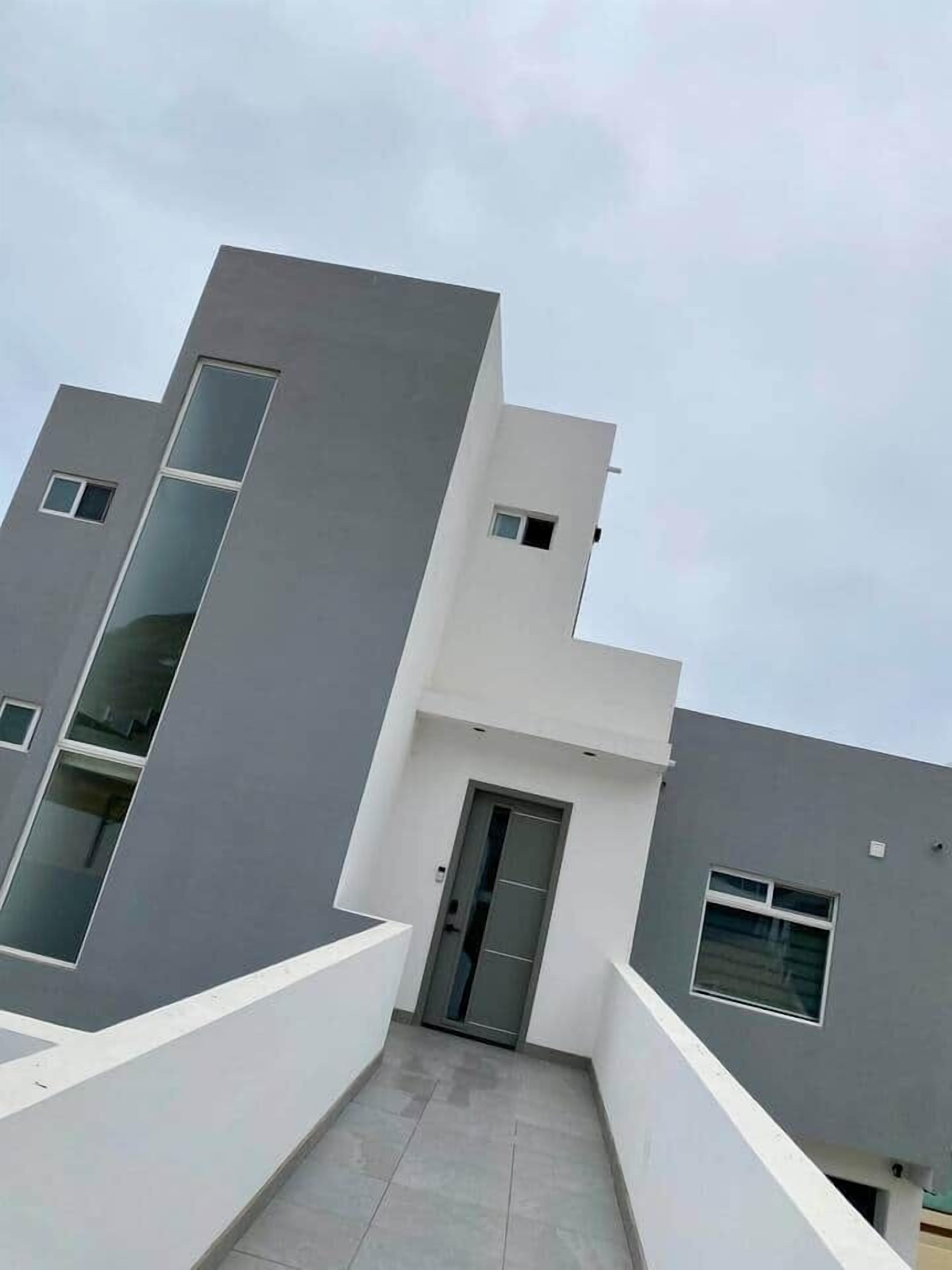 A modern building with a flat roof, a central door, and multiple windows.