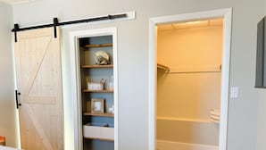 Quarto com cama, roupeiro com porta de celeiro deslizante e closet espaçoso com prateleiras e cestos.