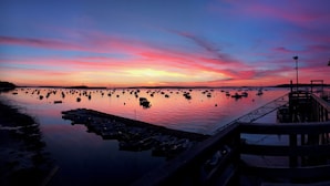 Um cais se estende por águas calmas, com barcos ancorados por perto.