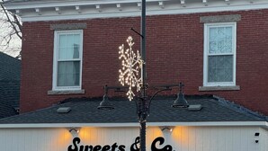 Fachada de loja com um letreiro indicando "Sweets & Co. bakery cafe" e uma placa de neon acima da entrada.