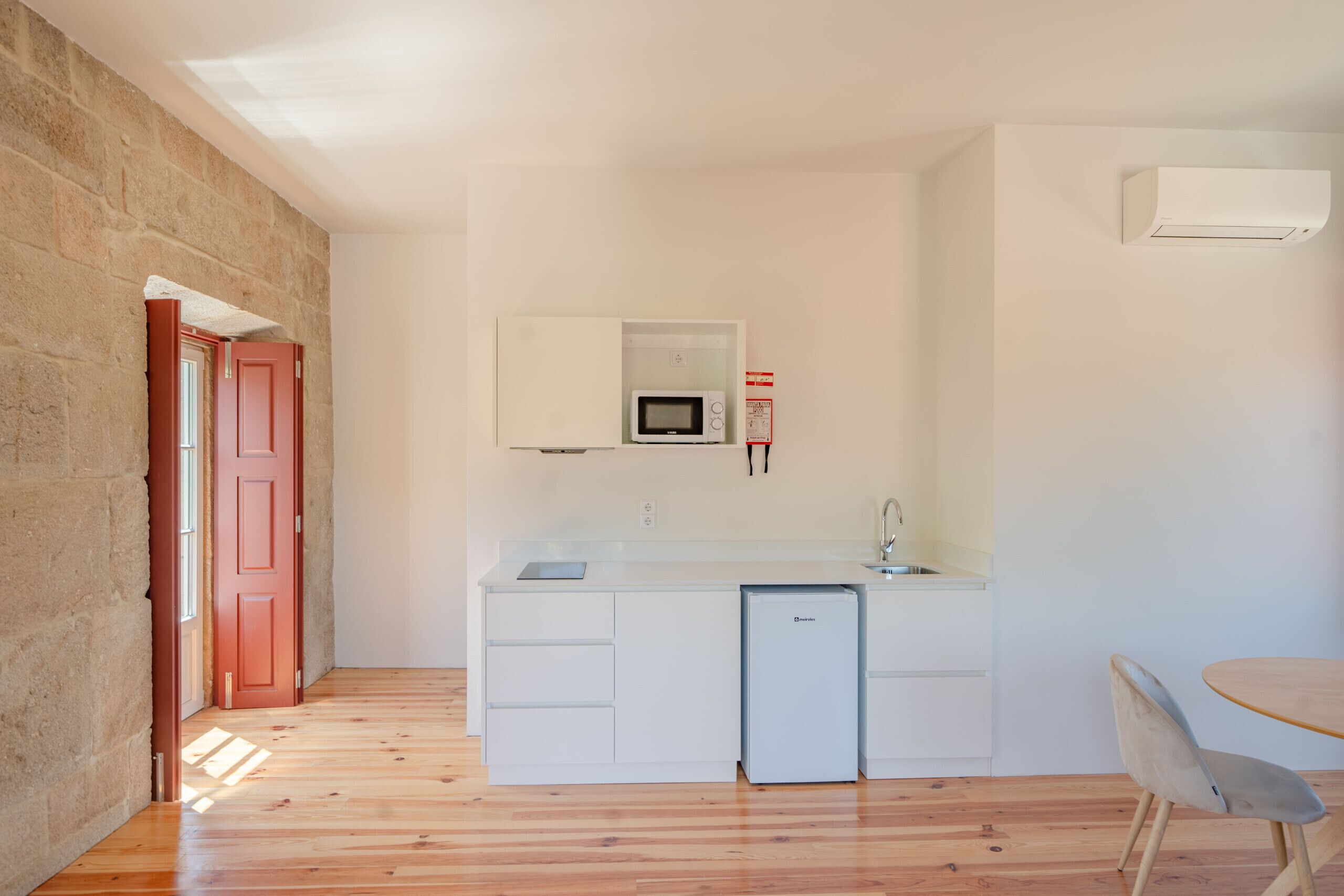 A compact kitchen with a built-in microwave, a small refrigerator, and a sink.