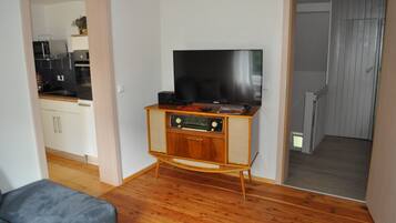 Uma sala de estar com um centro de entretenimento de madeira, uma TV de tela plana e um sofá cinza.