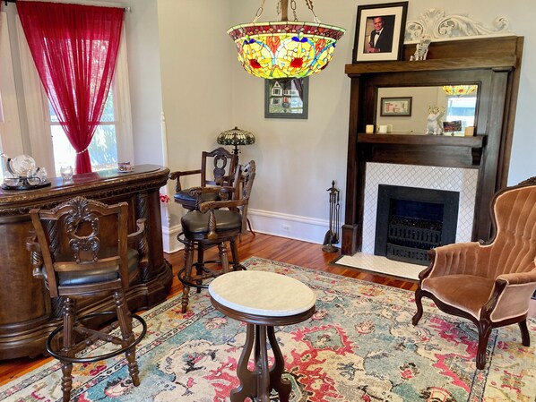 Un salon traditionnel avec une cheminée, un lustre et un tapis à motifs.
