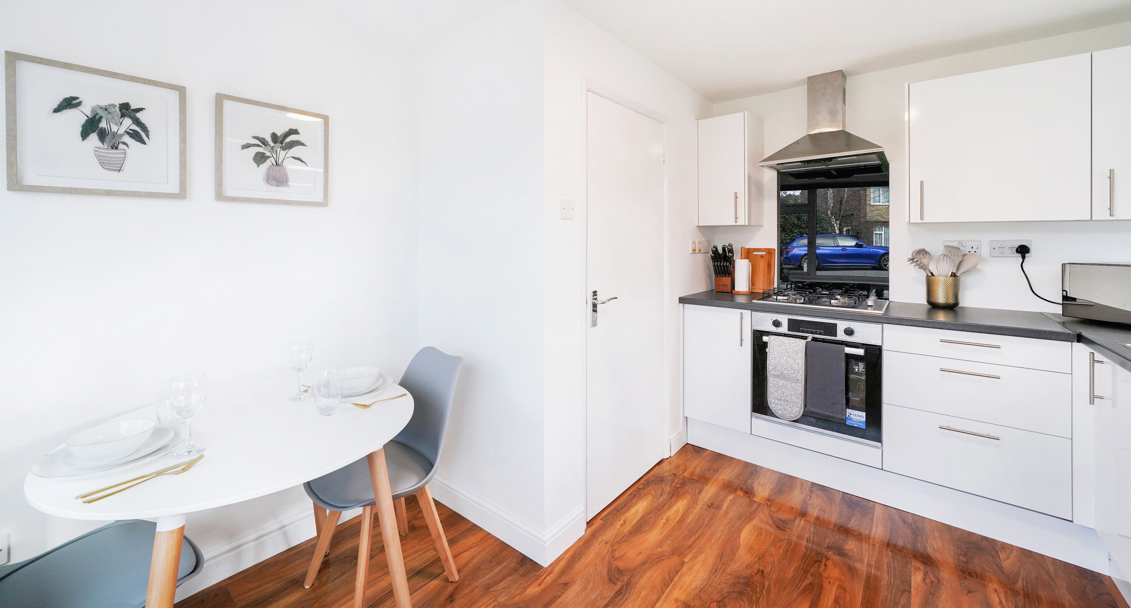 Una cocina moderna con gabinetes blancos, una estufa y un comedor con una mesa y sillas.
