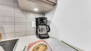 A kitchen with a coffee maker, a cookbook, and a tiled backsplash.