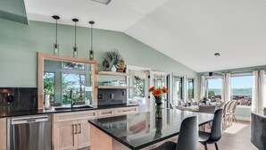 Een moderne keuken met een groot eiland, roestvrijstalen apparatuur en uitzicht op de omgeving.