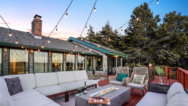 Een terras buiten met vuurkorf, zitgedeelte en lichtjes.