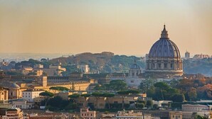 A cityscape with historic architecture, including a prominent dome and classical buildings. - Vatican rooms haven (Rome)