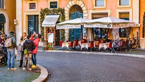 A cobblestone street with outdoor seating at a restaurant named 'Bernini Ristorante - Pizzeria'. - Vatican rooms haven (Rome)