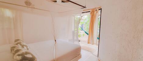 Un dormitorio con cama, ventana con cortinas y vista al exterior.
