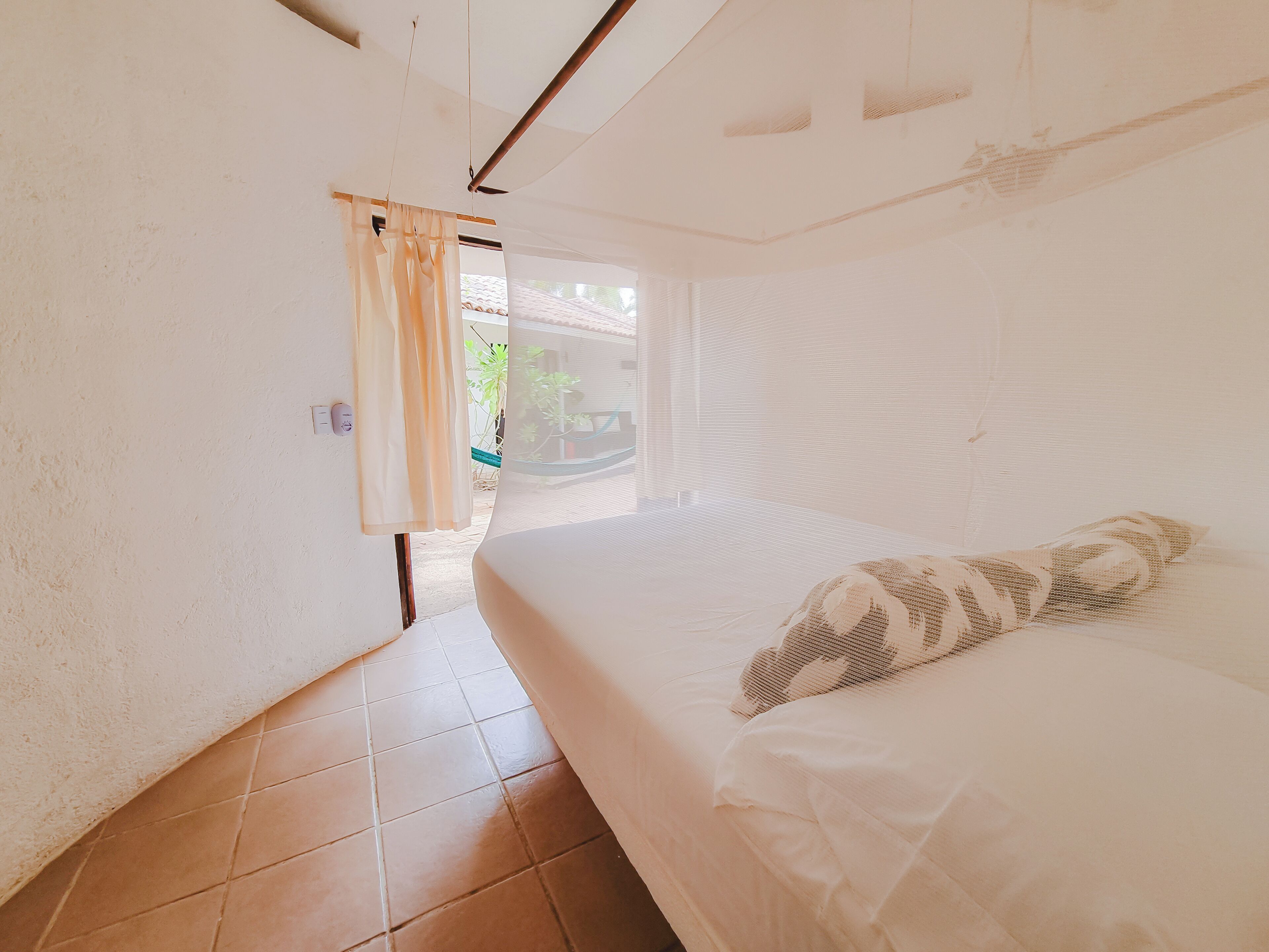 Una stanza con un letto, una finestra con tende e vista sull'esterno.
