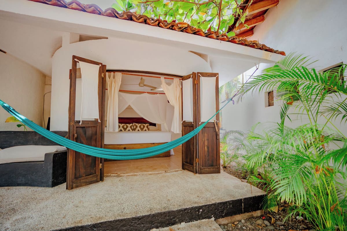 Ein Zimmer mit einem Bett, einer Hängematte und einem Deckenventilator.
