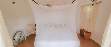 A single bed with a canopy, a ceiling fan, and a small bedside table.