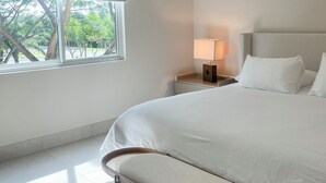 Une chambre à coucher moderne avec un grand lit, une table de chevet avec une lampe et une fenêtre équipée de stores.