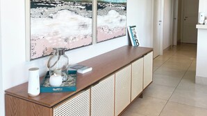 Un hall d’hôtel moderne avec une console en bois, une grande peinture abstraite et une vue sur le couloir.