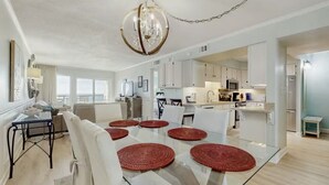 A modern living room with a glass dining table, white sofas, and a chandelier. - Fully updated 2025 Dream Oceanfront Sunset View. 2/2 Sleeps 8 (Fort Walton Beach)
