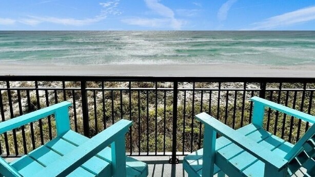 A balcony with turquoise chairs overlooking a beach with clear water and a rocky shoreline. - Fully updated 2025 Dream Oceanfront Sunset View. 2/2 Sleeps 8 (Fort Walton Beach)