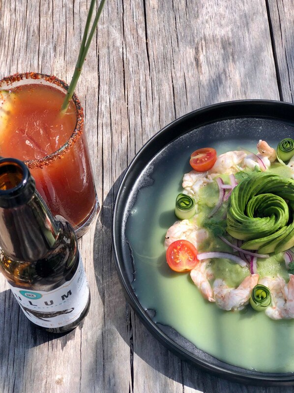 Une table avec un plat de fruits de mer, un cocktail et une bouteille de spiritueux.