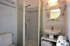 A bathroom with a toilet, shower, sink, and mirror. - Casa Meridiana (Calacuccia)