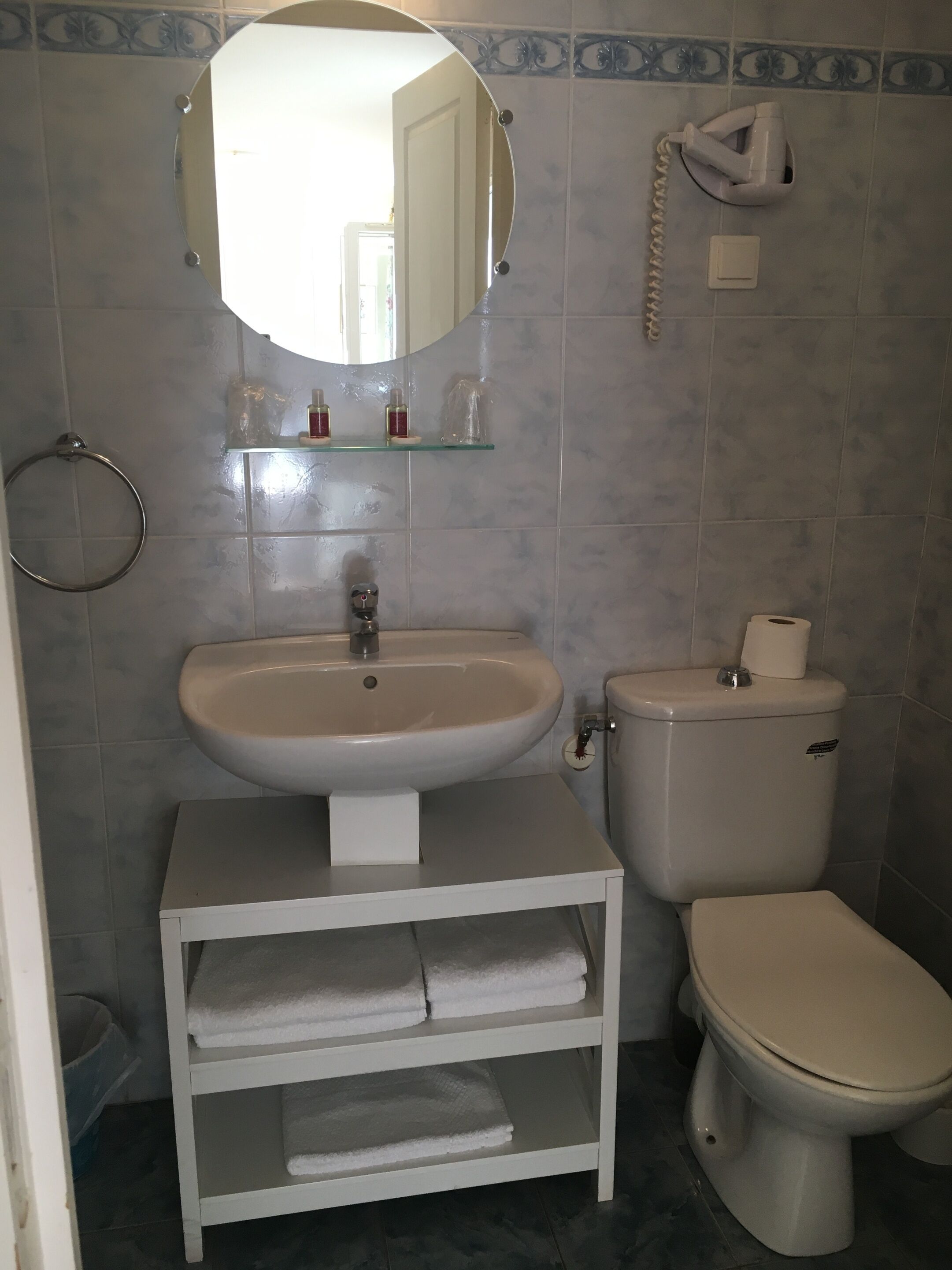 A bathroom with a sink, toilet, and a mirror.