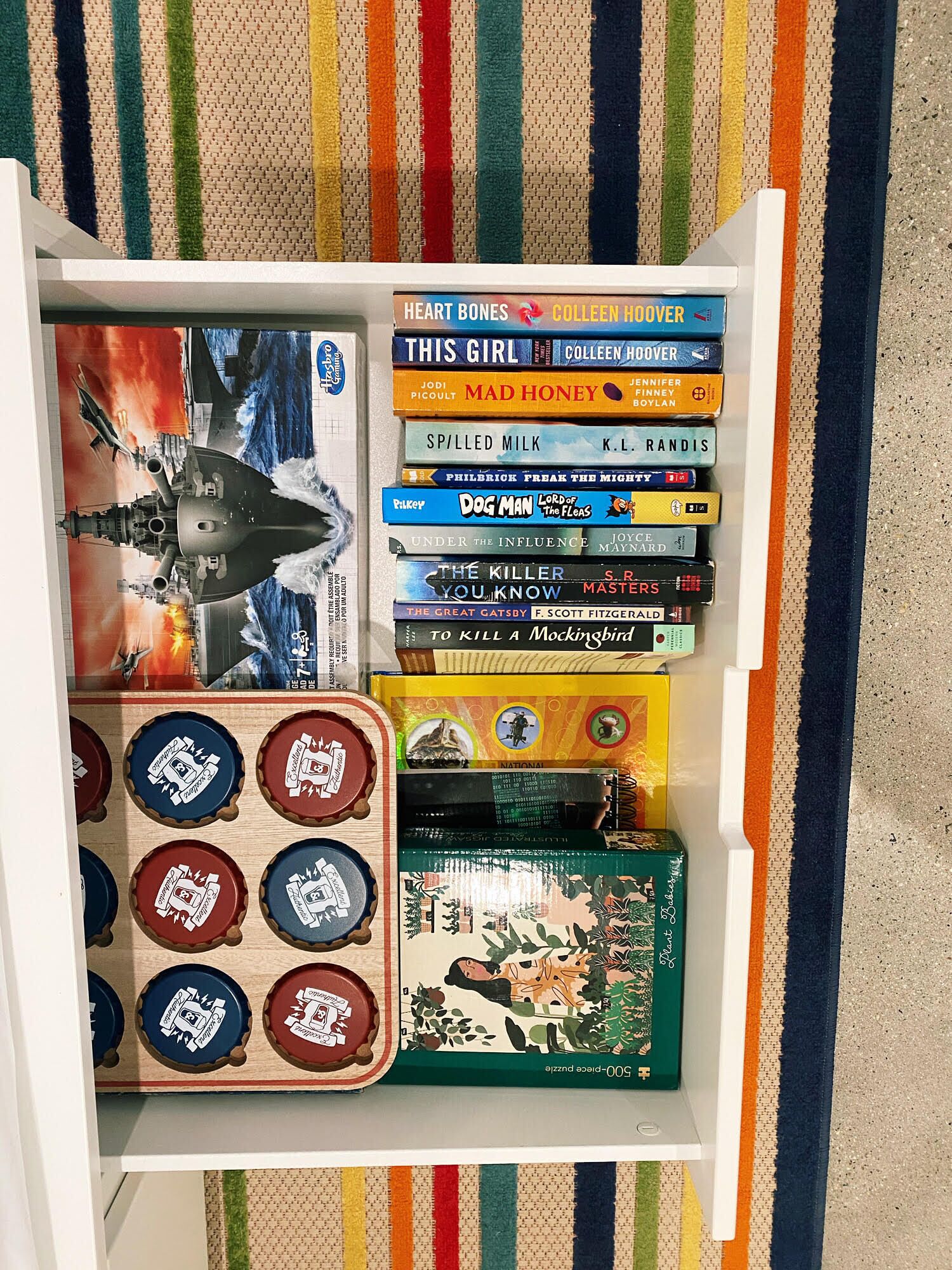 Une bibliothèque remplie de divers livres et une boîte de jeux de puzzle.
