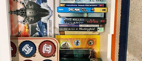 Une bibliothèque remplie de divers livres et une boîte de jeux de puzzle.