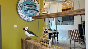 A wooden counter with a decorative sign, a bird sculpture, and various bottles. - Villa Ker Tesson: Private Jacuzzi, Port 700m, Fisherman's House, 10 guests (L'Île-d'Yeu)