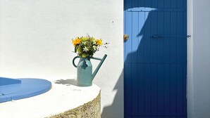 A blue door with a keyhole and a metal latch, a blue watering can with flowers, and a white wall. - Villa Ker Tesson: Private Jacuzzi, Port 700m, Fisherman's House, 10 guests (L'Île-d'Yeu)