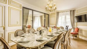 A dining room with a marble table set for six, surrounded by upholstered chairs.