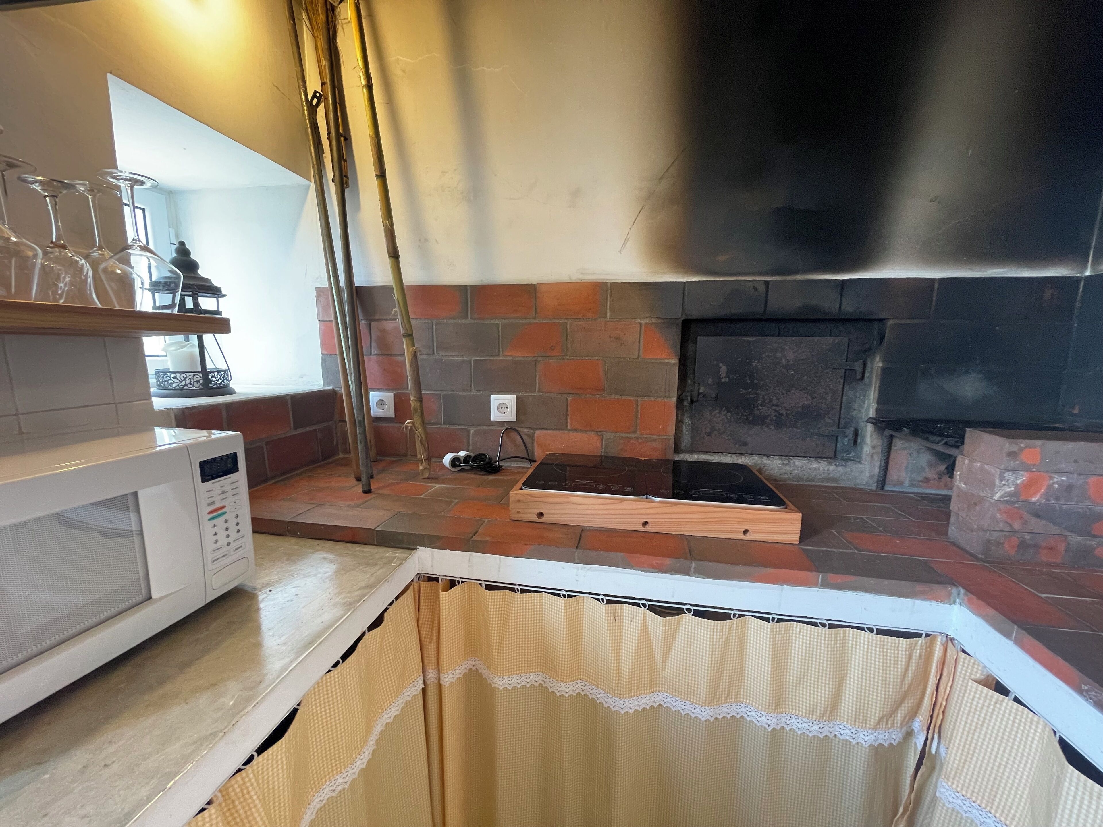 A kitchen with a brick wall, a microwave, and a wooden countertop.