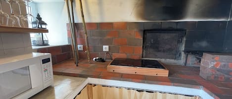 A kitchen with a brick wall, a microwave, and a wooden countertop.