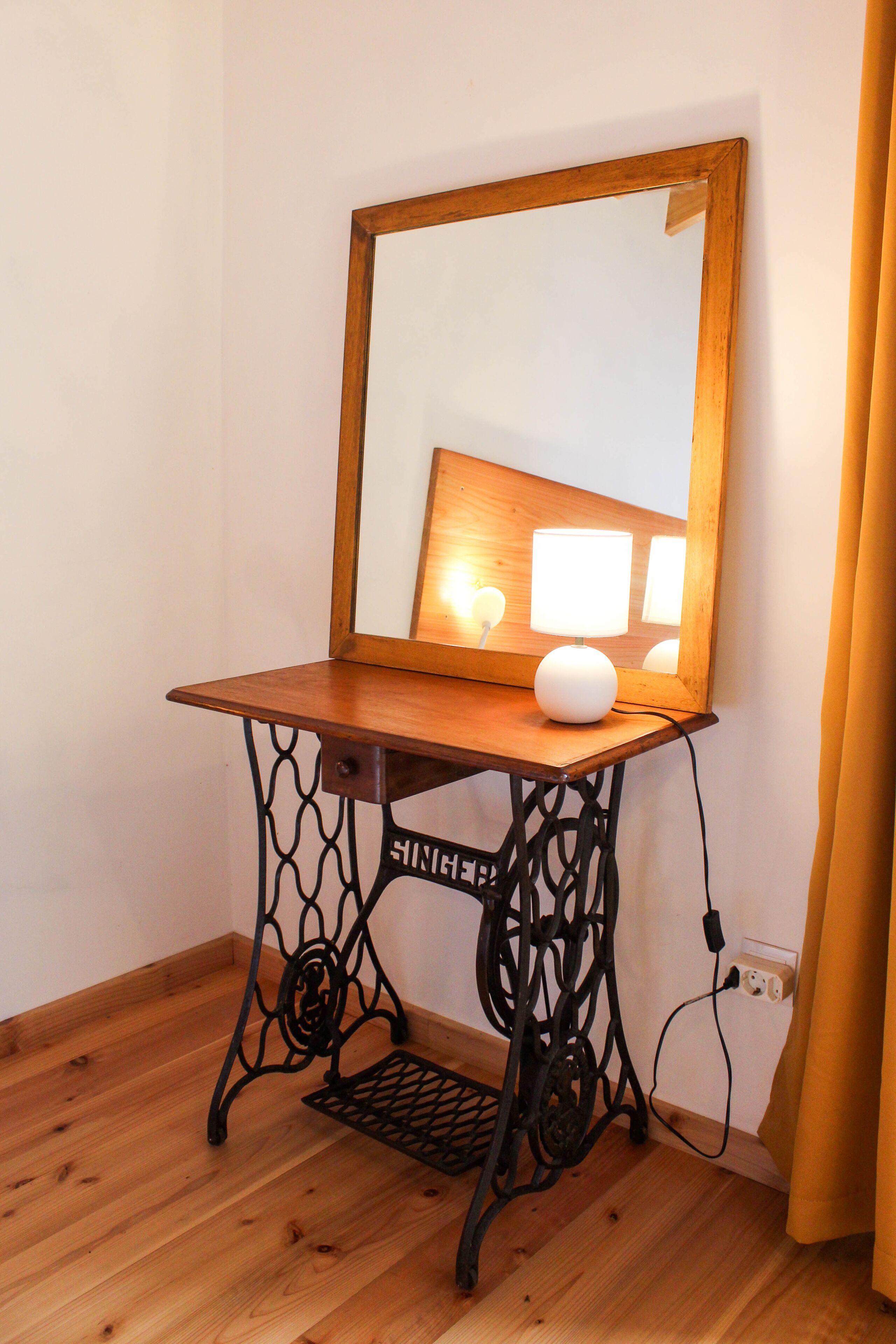 Ein Holznähtisch mit Spiegel, Lampe und Steckdose.