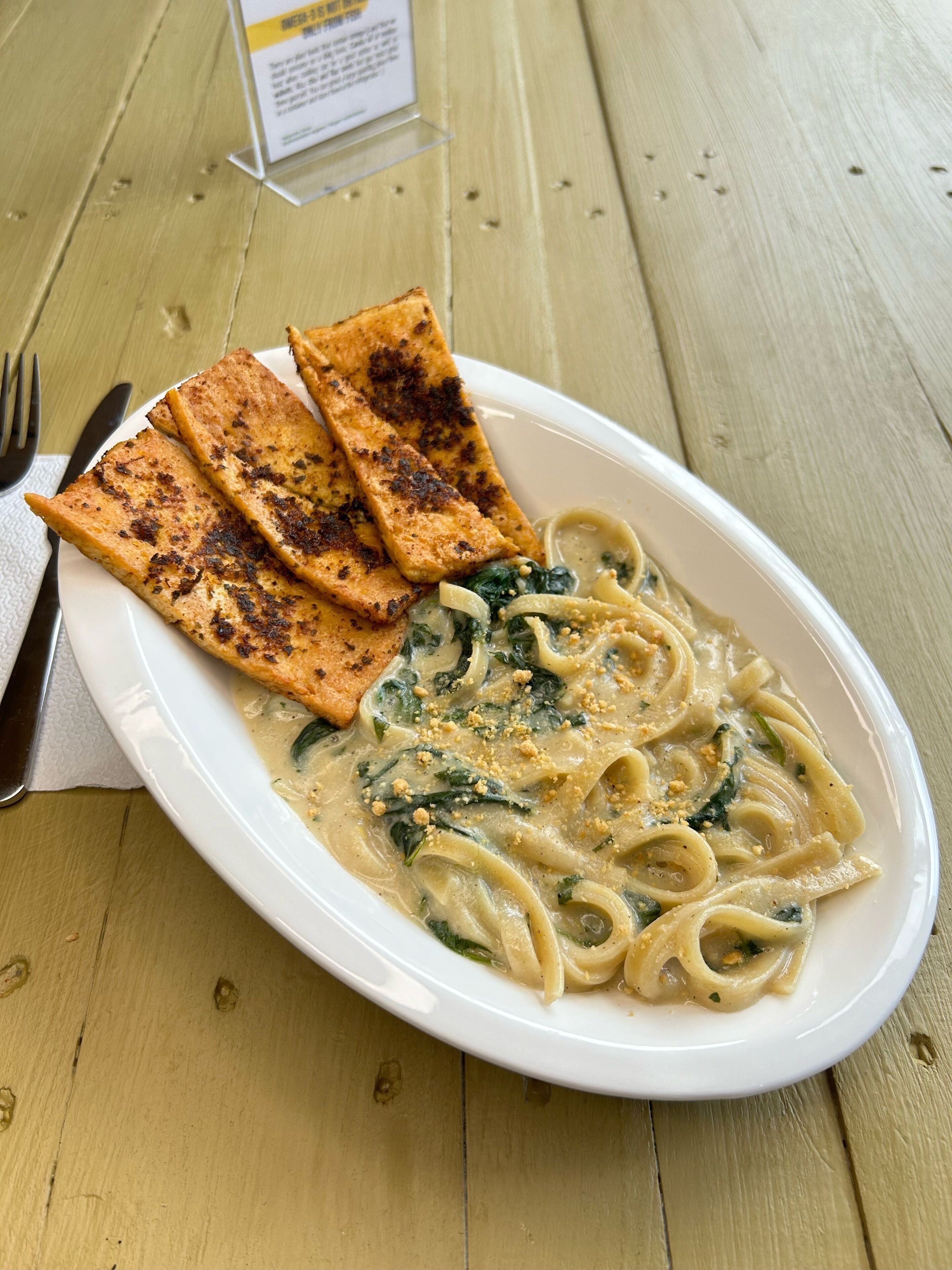 A plate of pasta with a creamy sauce and spinach, accompanied by grilled bread.