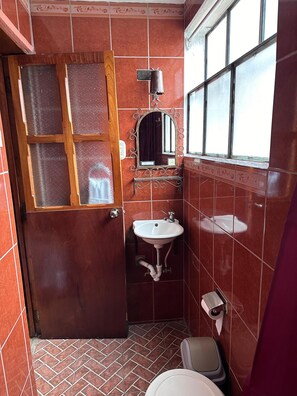 A bathroom with a wooden door, a mirror, a sink, and a toilet. - hotel casa blanca antigua guatemala  (Antigua Guatemala)