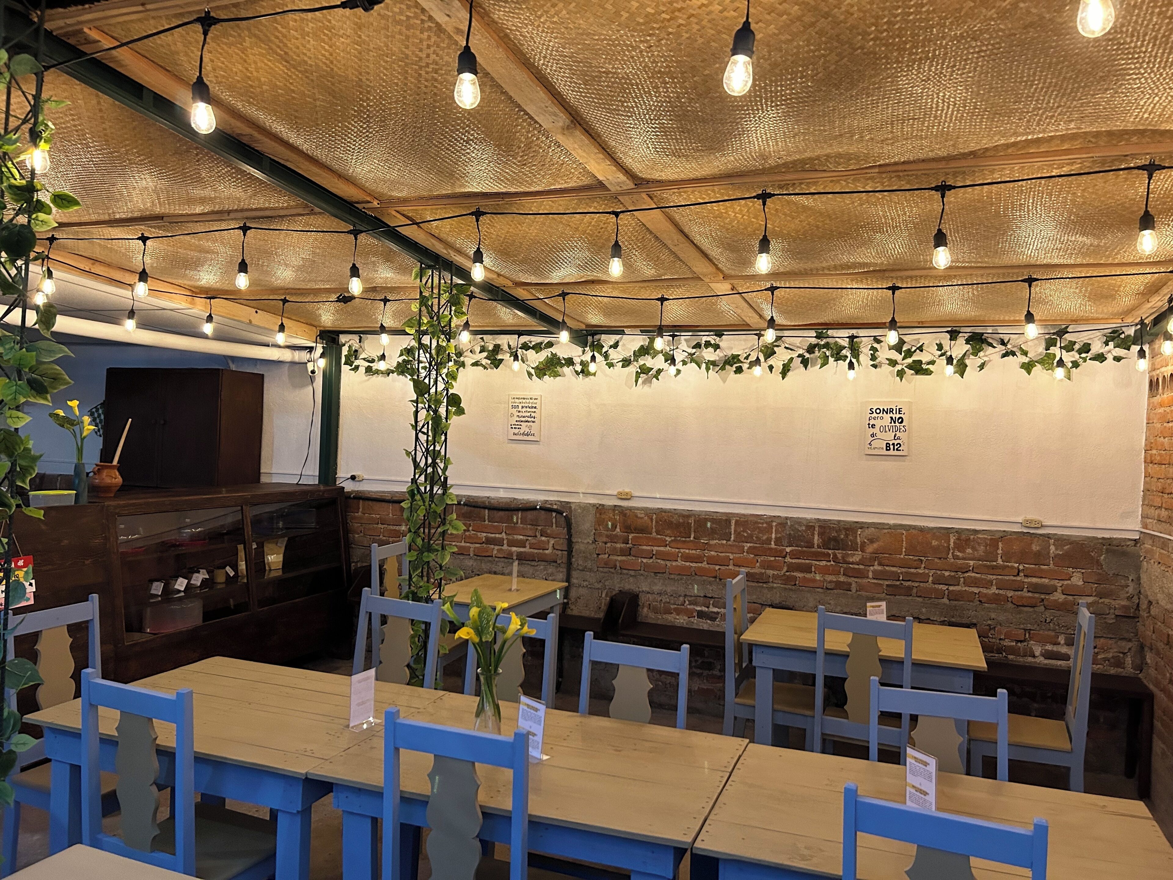A restaurant interior with brick walls, wooden tables, and hanging string lights.