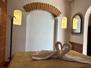 Ein Hotelzimmer mit Bett, Ziegelbogen, Wandspiegel und Stehlampe.
