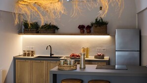 Eine moderne Küche mit integriertem Spülbecken, Holzschränken und einem Edelstahl-Kühlschrank. Auf der Arbeitsfläche stehen Korbwannen und eine Pendelleuchte ist angebracht.