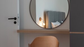 A modern room with a round mirror on the wall, a wooden chair, and a bed with a headboard. - Villa Eight by D (Okrug)