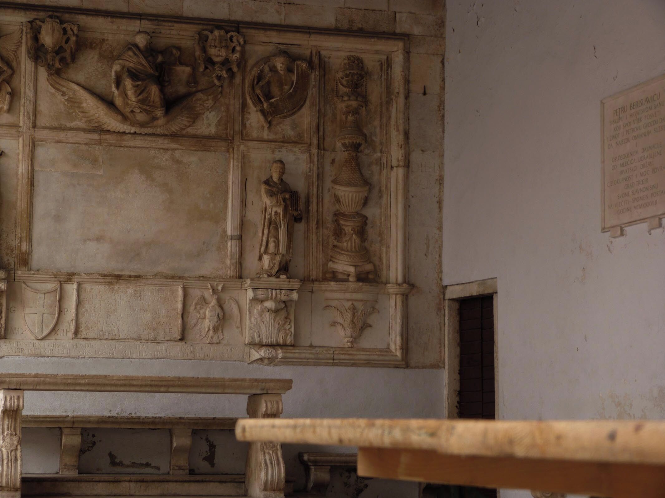 A detailed stone carving with various figures and symbols, likely part of a historical or religious building.