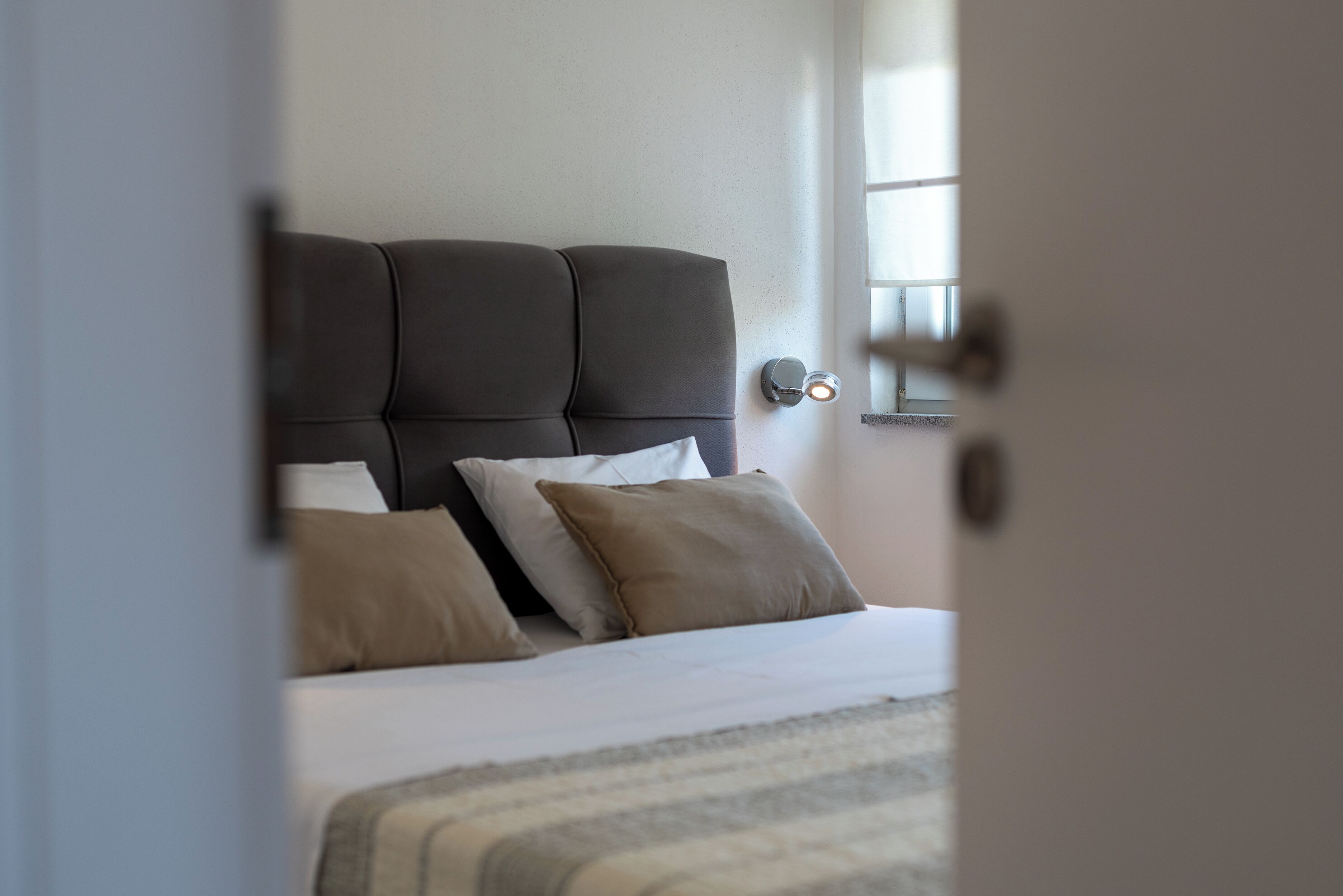 Ein Schlafzimmer mit einem Bett, Kissen, einem Kopfteil und einer Wandleuchte.