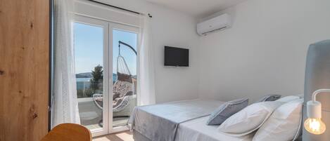 Een slaapkamer met een bed, een stoel, een televisie en uitzicht op de omgeving.