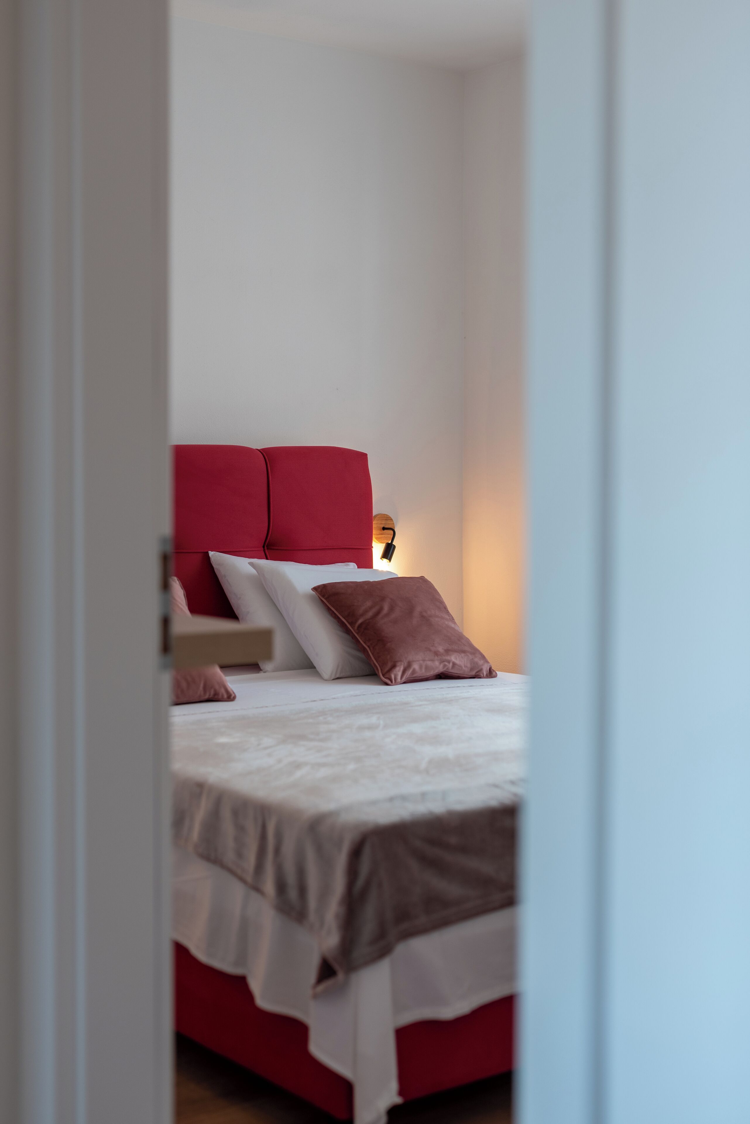 Un dormitorio con cama, almohadas y una lámpara de noche.