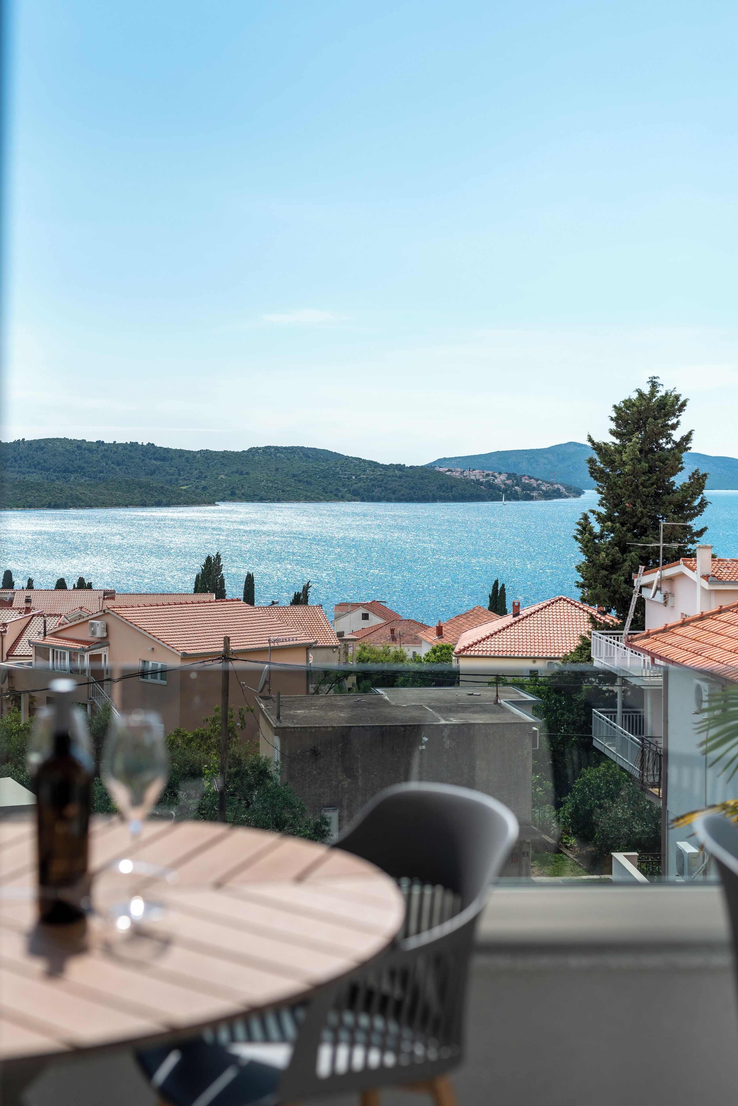 Una terraza con mesa y sillas que da a una masa de agua y un paisaje montañoso.