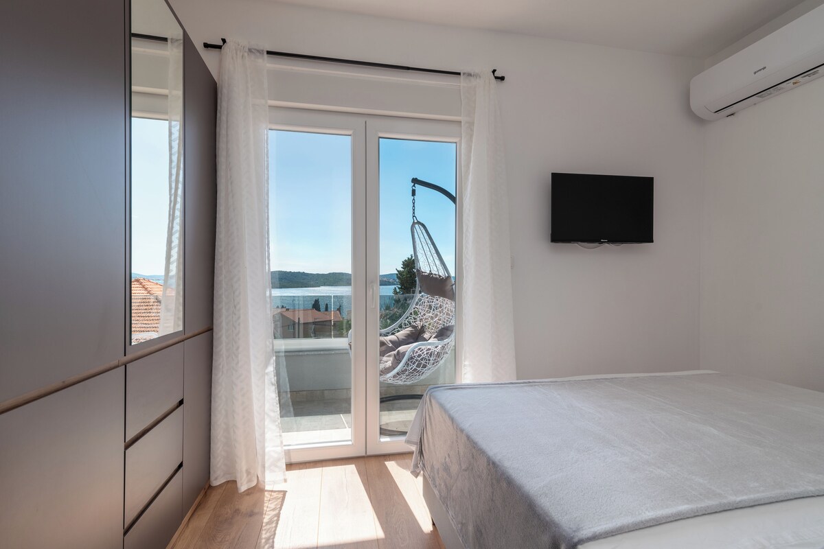 Un dormitorio con cama, televisor, puerta corrediza de vidrio y vistas a un puente.