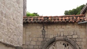 A stone building with a dark wooden door and a decorative archway above it. - Villa Eight by D (Okrug)