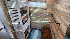 L’intérieur d’un chalet en bois, avec un lit superposé, une fenêtre et un petit rebord de fenêtre.
